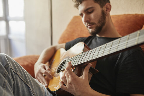 Mann spielt Gitarre auf Couch - JRFF01624