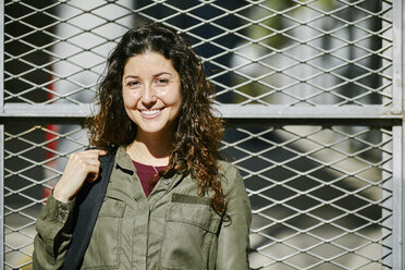 Portrait of smiling young woman at a fence - JRFF01628