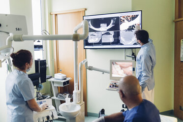 Dentist and dental nurse looking at dental x-rays - CUF03451