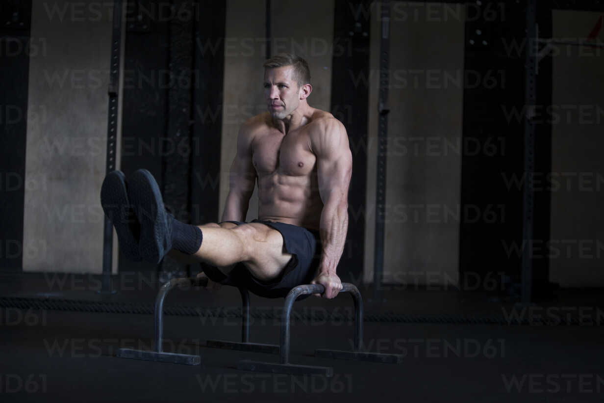 Man exercising in gymnasium, using parallel bars, in L-sit hold stock photo