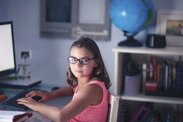 Porträt eines jungen Mädchens mit Brille, das am Schreibtisch sitzt und einen Computer benutzt - CUF03511