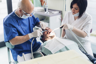 Dentist and dental nurse carrying out procedure on male patient - CUF03520