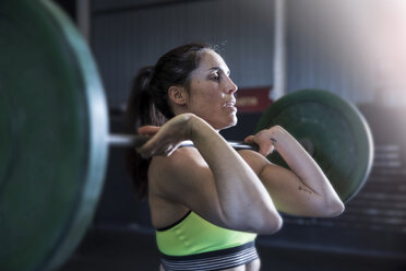 Frau trainiert im Fitnessstudio mit einer Langhantel - CUF03529