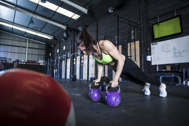 Woman exercising in gymnasium, using kettlebells - CUF03538