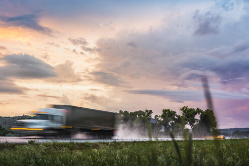 Fahrzeug auf nassem Highway bei Sonnenuntergang, Montana, USA - CUF03572