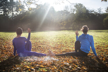 Zwei Frauen machen Yoga im Park an einem Herbsttag - CUF03603