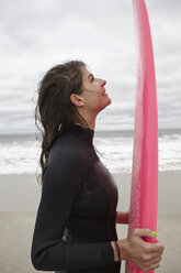 Porträt einer jungen Surferin mit rosa Surfbrett am Rockaway Beach, New York, USA - CUF03644