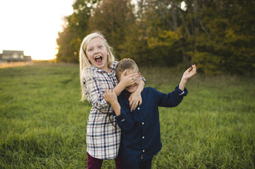 Sister covering brother's eyes smiling - CUF03647