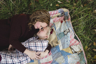 Mutter und Tochter liegen auf einer Decke und umarmen sich von Angesicht zu Angesicht - CUF03655