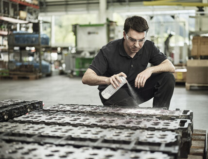 Arbeiter in einem metallverarbeitenden Betrieb beim Spritzen eines Zylinderkopfs - CVF00464