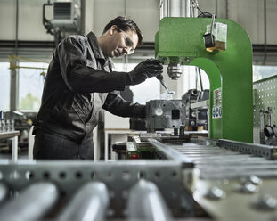 Arbeiter in einer metallverarbeitenden Fabrik beim Beladen eines Zylinderkopfs - CVF00466