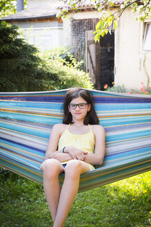Porträt eines lächelnden Mädchens, das in einer Hängematte im Garten sitzt - LVF06959