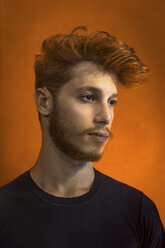 Portrait of young man with red hair against orange background - CUF03768