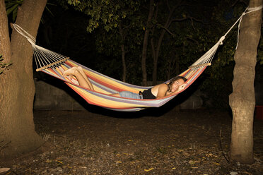 Young woman asleep in hammock at night - CUF03780