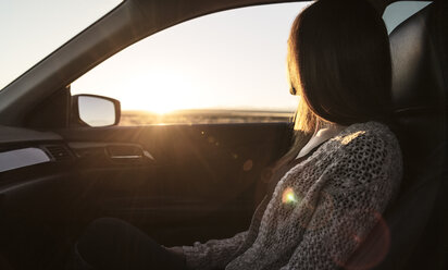 Junge Frau sitzt auf dem Beifahrersitz eines Autos und schaut aus dem Fenster - CUF03812