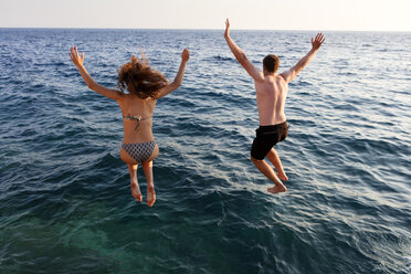 Young couple jumping into sea, rear view, Orebic, Croatia - CUF03821