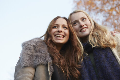 Zwei Freundinnen, die im Freien spazieren gehen, lächelnd - CUF03934