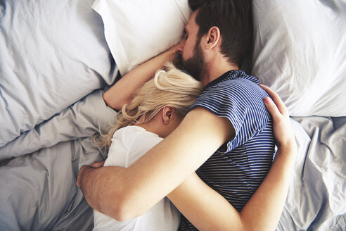 Paar, das zusammen im Bett liegt und schläft, die Arme umeinander gelegt - CUF03946