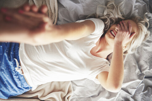 Frau auf dem Bett liegend, Mann zieht sie aus dem Bett, Blick von oben - CUF03950