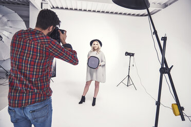 Male photographer photographing female model on studio white background - CUF03954