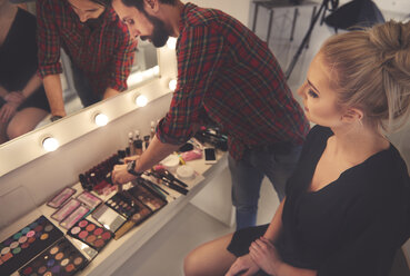 Männlicher Visagist bei der Auswahl des Make-ups für ein Fotoshooting - CUF03975