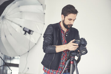 Männlicher Fotograf, der ein Studio-Foto-Shooting auf einer digitalen Spiegelreflexkamera überprüft - CUF04010