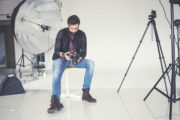 Male photographer reviewing studio photo shoot on digital slr - CUF04011