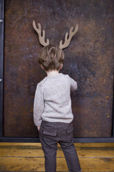 Junge steht vor einer Wand, hinter ihm ist ein Rentier aus Pappe ausgeschnitten - CUF04061