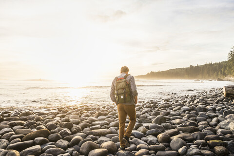 Rückansicht eines Mannes, der am Strand im Juan de Fuca Provincial Park spazieren geht, Vancouver Island, British Columbia, Kanada, lizenzfreies Stockfoto