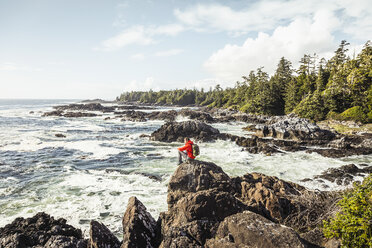 Male hiker looking out to sea from rocky coast, Wild Pacific Trail, Vancouver Island, British Columbia, Canada - CUF04093