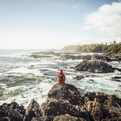 Male hiker looking out to sea from rocky coast, Wild Pacific Trail, Vancouver Island, British Columbia, Canada - CUF04094