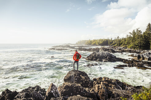 Männlicher Wanderer, der von der felsigen Küste aufs Meer hinausschaut, Wild Pacific Trail, Vancouver Island, British Columbia, Kanada - CUF04095