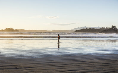 Man strolling on Long Beach at sunrise, Pacific Rim National Park, Vancouver Island, British Columbia, Canada - CUF04099