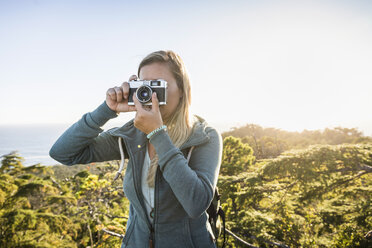 Female hiker photographing coastal forest, Pacific Rim National Park, Vancouver Island, British Columbia, Canada - CUF04103