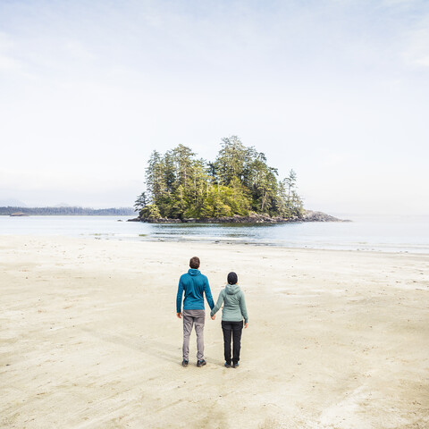 Paar mit Blick auf die Insel vom Long Beach, Pacific Rim National Park, Vancouver Island, British Columbia, Kanada, lizenzfreies Stockfoto