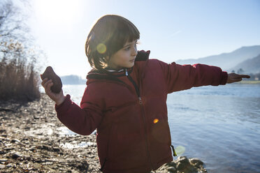 Young boy beside lake, throwing stone into lake - CUF04135