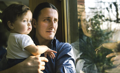 Mature man and baby son looking through window - CUF04140