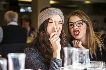 Porträt von zwei jungen Frauen, die in einem Café Grimassen schneiden - CUF04147
