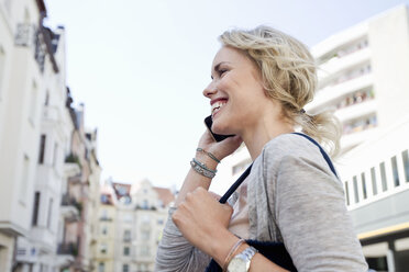 Mid adult woman strolling in city making smartphone call - CUF04168