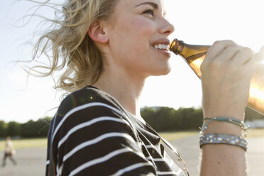 Mid adult woman drinking bottled beer outdoors - CUF04221