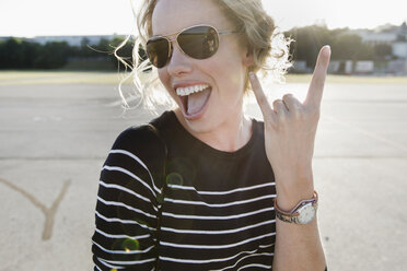 Portrait of mid adult woman wearing sunglasses making hand gesture - CUF04223