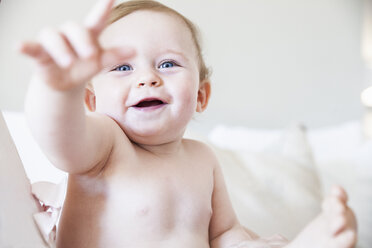 Porträt eines glücklichen kleinen Jungen, der aus dem Bett zeigt - CUF04257