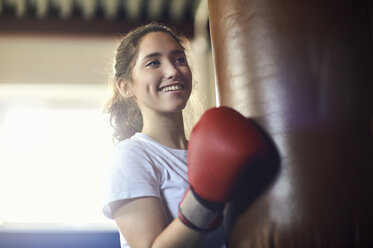 Young female boxer punching punch bag in gym - CUF04291