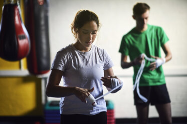 Young male and female boxers wrapping hands in bandages - CUF04296