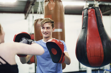 Weiblicher Boxer beim Training, schlägt auf den Boxhandschuh eines Teamkollegen - CUF04307