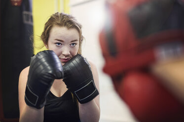 Young female boxer poised to box punch mitt - CUF04308