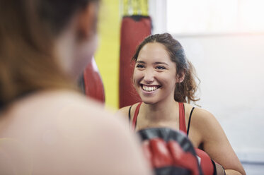 Over shoulder view of female boxer training, punching teammates punch mitt - CUF04312