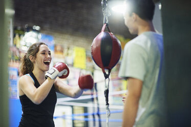 Junger weiblicher Boxer, der im Fitnessstudio auf einen Sandsack einschlägt - CUF04319