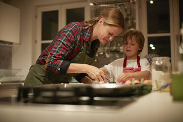 Reife Frau hilft Sohn beim Backen auf der Küchentheke - CUF04371
