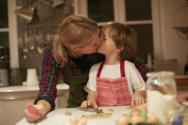 Woman kissing son whilst baking at kitchen counter - CUF04373